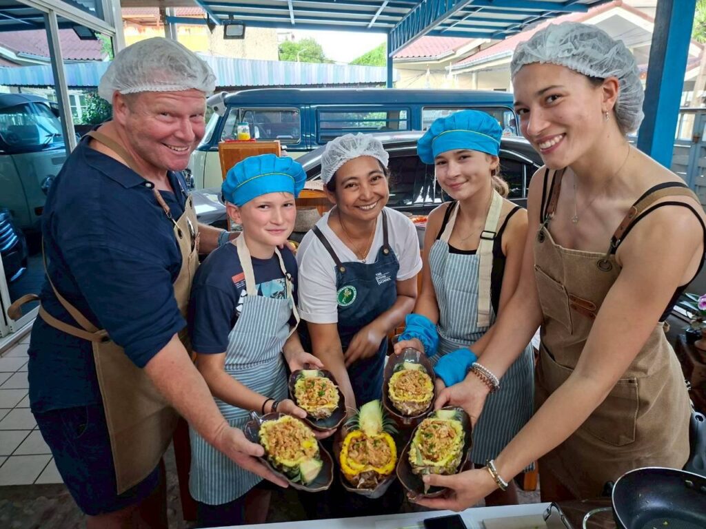 Guests holding pineapple fried rice during Thai cooking class at Baan Suan Hin Lek Fai, Hua Hin. A fun and family-style culinary experience with Uncle and Aunty House.